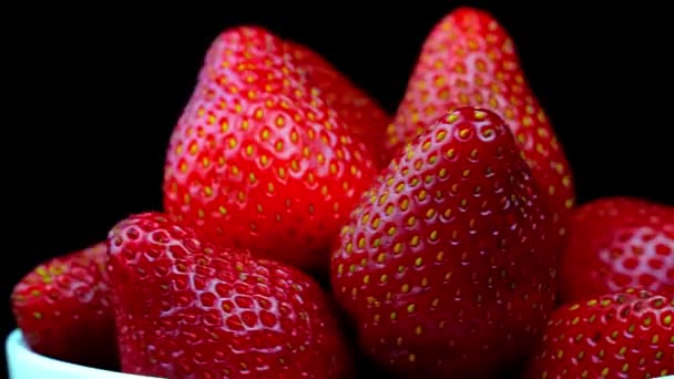 Strawberries without tails lie in white bowl or plate. It rotates — Video