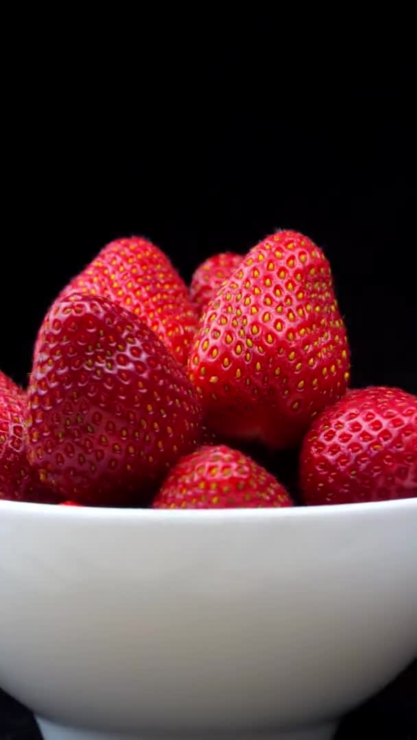 Fresas sin colas se encuentran en un tazón blanco o plato. Rota. — Vídeo de stock