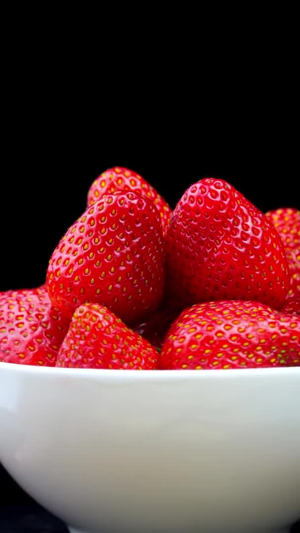 Fresas sin colas se encuentran en un tazón blanco o plato. Rota. — Vídeo de stock