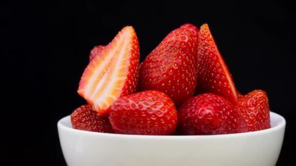Strawberries without tails lie in white bowl or plate. It rotates — ストック動画