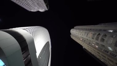 Kameralar gece yüksek gökdelenleri gören daireler çizer.