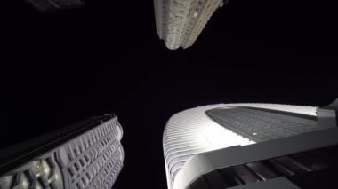 Camera rotates in circle with view of tall skyscrapers at night