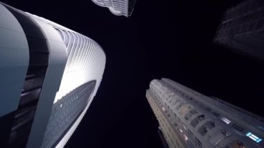 Camera rotates in circle with view of tall skyscrapers at night