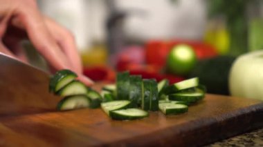 Female housewife prepares healthy food in kitchen. She cuts vegetables,