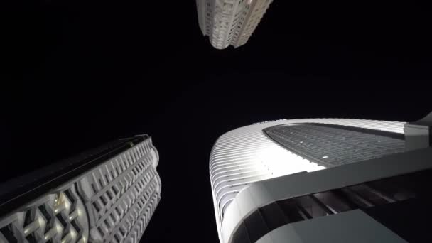 Fotoaparát se otáčí v kruhu s výhledem na vysoké mrakodrapy v noci — Stock video