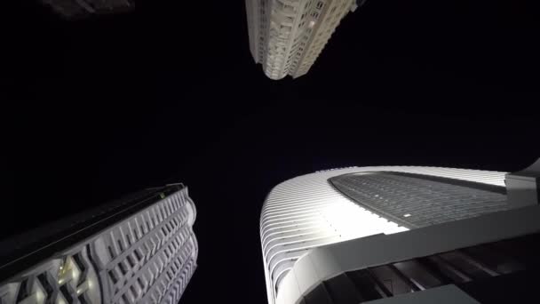 Camera rotates in circle with view of tall skyscrapers at night — Wideo stockowe