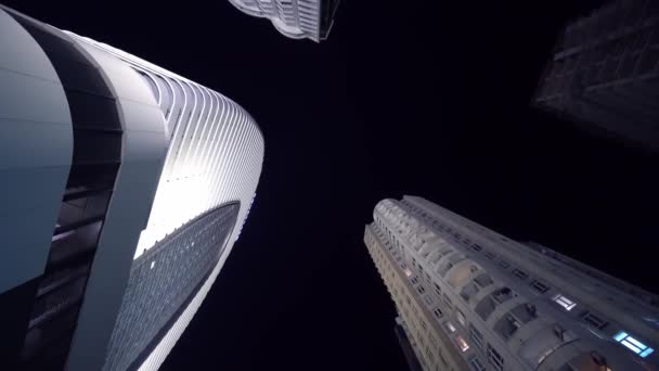 Camera draait in cirkel met uitzicht op hoge wolkenkrabbers 's nachts — Stockvideo