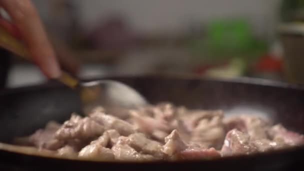 Woman's hand spoons meat in frying pan. Close-up. — Stok video
