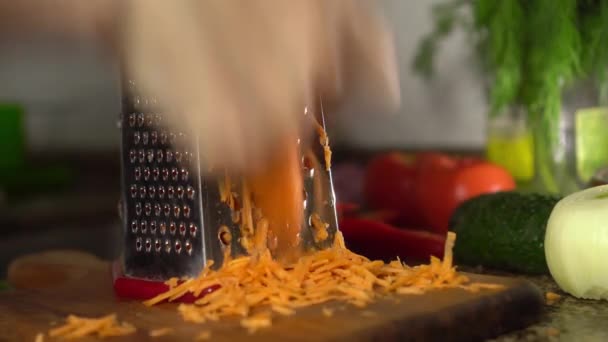 Female hands rub carrots on table against background of vegetables and herbs. — Wideo stockowe