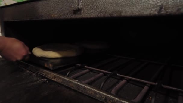 Bäcker legt Brotteig mit Schaufel in den Ofen. — Stockvideo