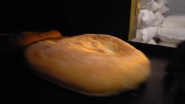 Baker removes cooked bread from oven with his hands — Stok Video