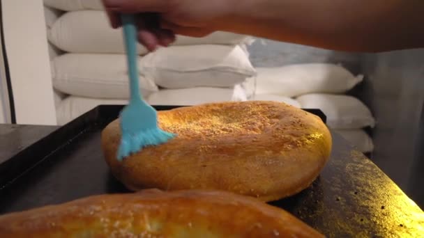 A cook combing melting butter with brush on baked bread — Stock video