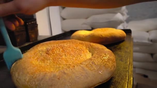 A cook combing melting butter with brush on baked bread — Stockvideo