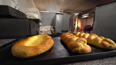 Ekmek ve ekmek şeklinde fırınlanmış hamur işleri arkaplan fırınına karşı masada yatar.