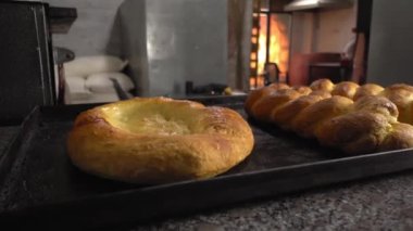 Ekmek ve ekmek şeklinde fırınlanmış hamur işleri arkaplan fırınına karşı masada yatar.