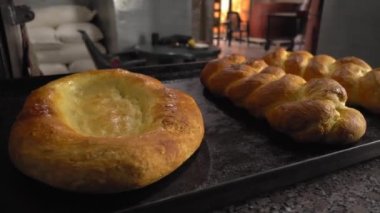 Ekmek ve ekmek şeklinde fırınlanmış hamur işleri arkaplan fırınına karşı masada yatar.