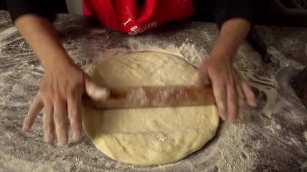 Chef rocks dough with rolling pin on kitchen table against background of flour — Video Stock