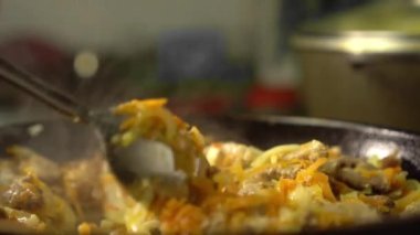 Frying pan with meat and vegetables close-up. Female rka mixes contents.
