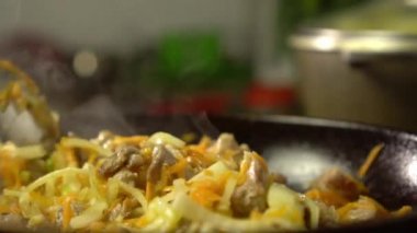 Et ve sebzeli kızartma tavası. Dişi rka içeriği karıştırır.