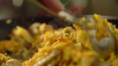 Et ve sebzeli kızartma tavası. Dişi rka içeriği karıştırır.