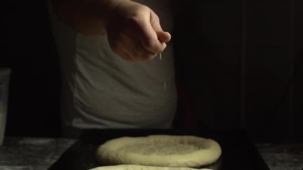 Tattooed hand pours sesame seeds or salt on bread, — ストック動画