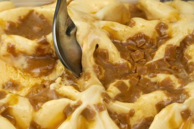 Karamelli dondurmayı tatlı kaşığıyla kepçelemeye yakın çekim. Karamelli dondurmanın makro fotoğrafı.