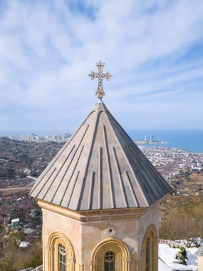 Güneşli bir günde, Gürcistan 'ın başkenti Adjara' daki Sameba Dağı 'ndaki Kutsal Üçleme Kilisesi' ne kar, şehir ve deniz manzarası kalıntılarıyla birlikte. Dikey fotoğraf