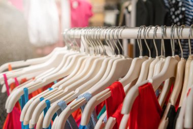 Alışveriş merkezindeki parlak yazlık elbiseli askılara yakın çekim. Mağazada kadın kıyafetleri var.