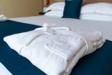 Close-up of a folded white terry robe on the bed