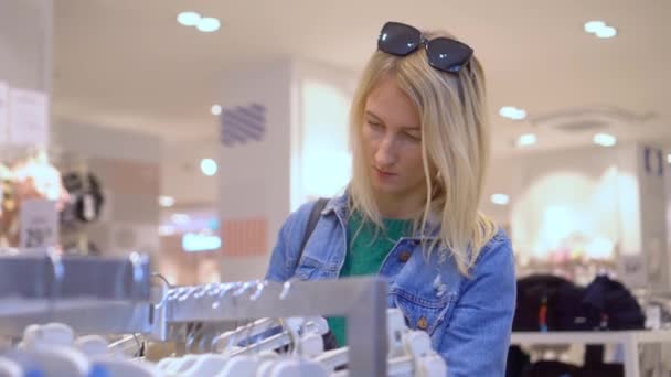 Красивая Молодая Кавказка Белыми Волосами Выбирает Одежду Магазине Торговом Центре — стоковое видео