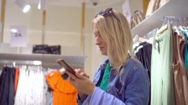 Genç ve güzel bir Bulrndinka kadını giyim mağazasında ya da alışveriş merkezinde akıllı telefon kullanıyor. Ona elbise seçiyor ve kuryeyle mektuplaşıyor. Arkadaşlara, sosyal ağlara danışmanlık.