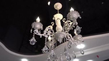Close-up of beautiful crystal chandelier Beautiful chandelier. luxurious expensive chandelier suspended from ceiling. Old luxury on black glossy suspended ceiling. Camera flyby.