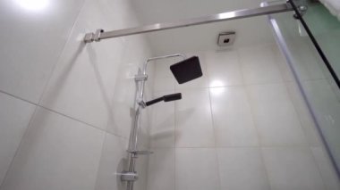 Banyoda eski gri çiçeklerle modern yenileme. Duş başlığı yağmuru. Beyaz tavan. Modern duş kabini. Yakın plan. Kamera hareketi.