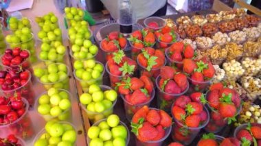 Market Gürcistan 'da, plastik bardaklarda kurutulmuş meyve, fındık, çilek ve kiraz eriği bulunuyor. Spontane piyasa. Yerel lezzetlerle dolu bir masa. Kamera hareketi. Meyve ve sebzeli tezgah..