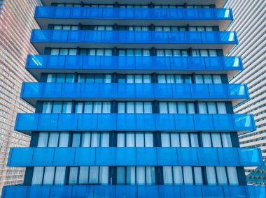 Birçok pencere ve balkonu olan modern çok katlı bir binanın insansız hava aracının yakın görüntüsü. Çok katlı mavi cam bina, apartmanlar, otel.
