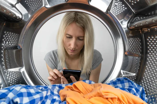 Young Woman Looks Thoughtfully Mobile Phone Photo Drum Washing Machine — Foto de Stock
