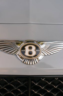 Batumi, Georgia - May 11 2022: Close-up of the Bentley badge of 1919-2019 on the light hood of the car. Vertical photo