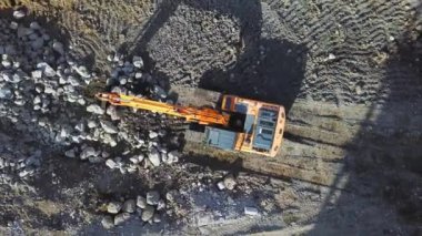 Large yellow excavator or bulldozer takes stones with bucket and fills hole or in large puddle where water is collected. Construction site. construction. Heavy machinery is digging ground.