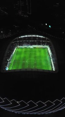 View of stadium with football field in middle of city of Batumi in Georgia. visible from above at night with stadium lights on and athletes playing football. Drone flight around playground altitude.