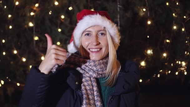 Woman Santa Claus Hat Gives Thumbs Background Night City Garland — Stockvideo