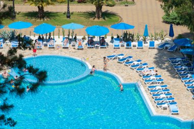Chakvi, Georgia - 12 Haziran 2022: Tatilciler güneşli bir günde otel havuzunda yüzer ve güneşlenirler.