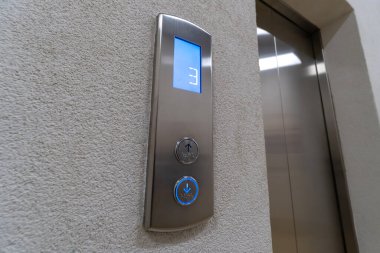 Asansör çağırma düğmelerini Braille alfabesiyle kapatın. Asansörün oku asansörün üçüncü kattaki hareketini gösteriyor.