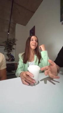 Üniversitedeki kafede sohbet eden bir grup arkadaş, kahkahalar atıyorlar. Kafede oturup bir fincan kahve ve suyla sohbet eden mutlu genç arkadaşların portresi. Arkadaşlar eğlenir. dikey video