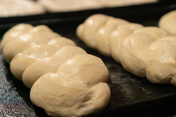 Close-up of a bun or bakery product in the form of a pigtail on a baking sheet before baking in the oven, raw dough