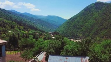 Gürcistan 'daki dağ köyünün resimli manzarası, yazın mükemmel ışıklandırması var. Hepsi yeşil bitki örtüsü, evler dağların eteklerinde duruyor. Üzüm bağları. Adjara, Türkiye sınırı. Uçan İHA
