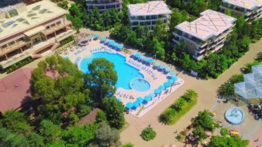 Tatilciler güneşli bir günde otel havuzunda yüzer ve güneşlenirler..