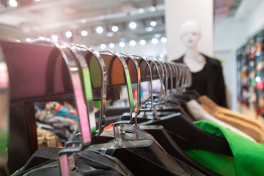 Alışveriş merkezindeki parlak yazlık elbiseli askılara yakın çekim. Mağazada kadın kıyafetleri var.