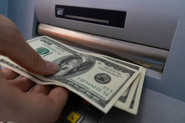 Close-up of a woman\'s hand withdrawing money from an ATM. Selective focus