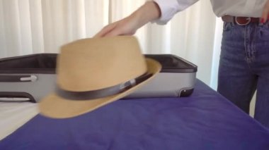 A young beautiful woman in a Santa Claus hat puts things out of a suitcase after a vacation or before a vacation. With a smile on her face, she is going to rest. Apartment or hotel room. Christmas.