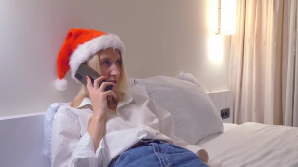 Relaxed Woman Santa Claus Hat Home Talking Her Smartphone Her — ストック動画